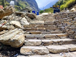 Rugged stone steps lead upward, flanked by rocky terrain and retaining walls.
