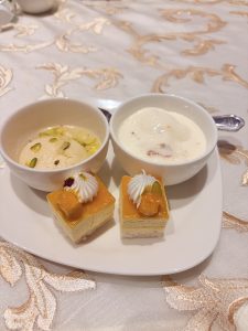 An Indian dessert featuring cheesecake served with rasgulla in a bowl.