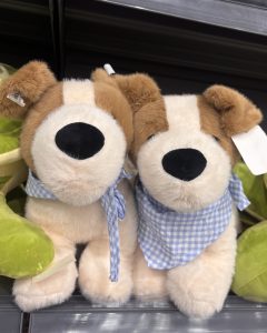 Two plush puppy toys sit side by side, both wearing blue checkered bandanas.