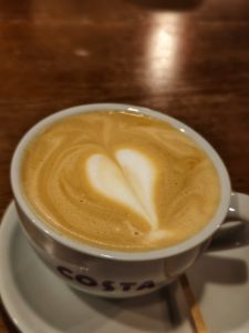 Closeup of a coffee cup with a heart formed in the foam on top.