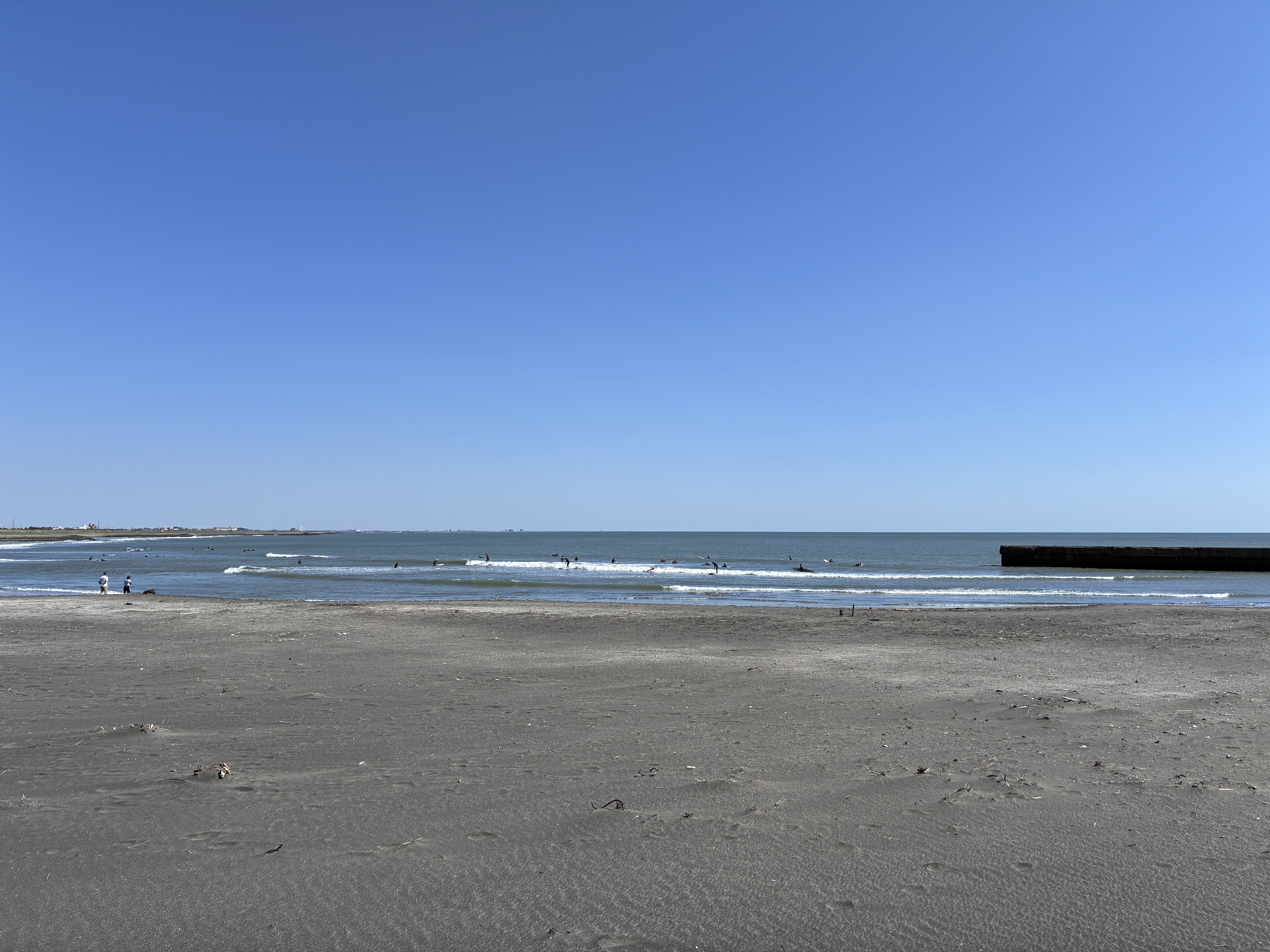 A serene beach scene featuring gentle waves lapping the shore under a clear blue sky.