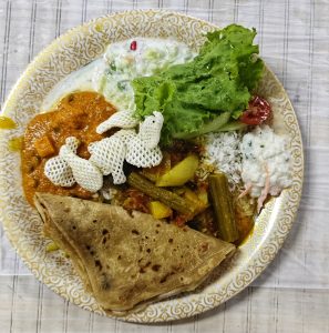 
A round plate with a variety of Indian dishes.