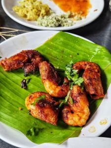 


A plate featuring several pieces of grilled Prawns arranged on a green banana leaf.