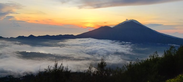 Sunrise over mist-covered mountains with clouds filling the valley below.