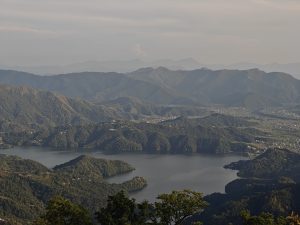 Sweeping aerial view of Phewa Lake winding through misty green hills and valleys 