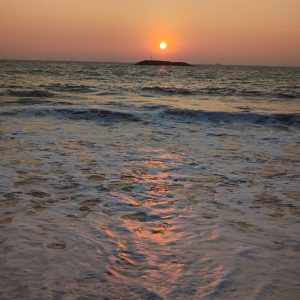 Sunset over the ocean with a vibrant orange sky.
