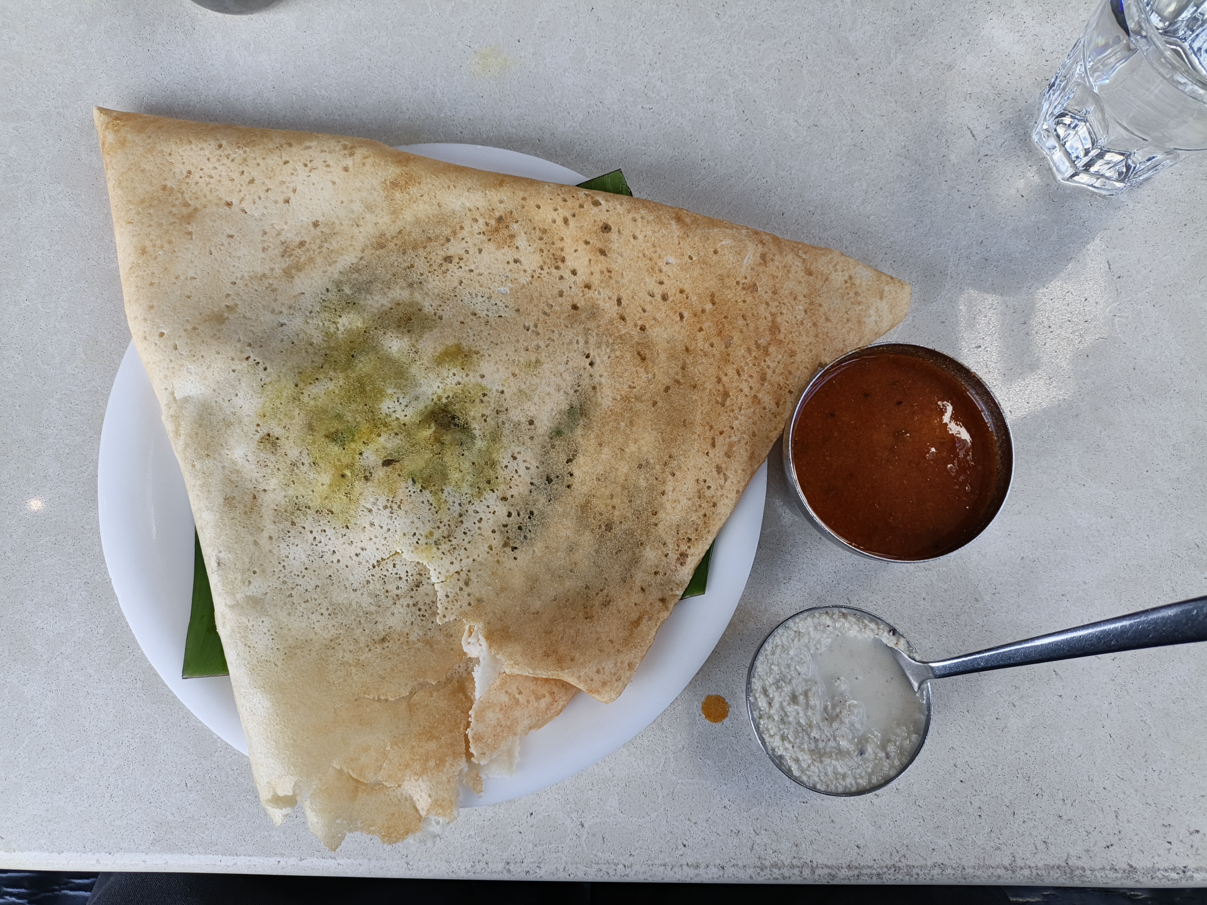 A traditional South Indian masala dosa served on a white plate with flavorful sambar and fresh coconut chutney. This crispy, golden rice and lentil crepe is filled with seasoned potato masala, offering a delicious combination of texture and authentic Indian flavors. A popular choice for breakfast, lunch, or dinner.