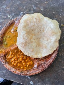A delicious plate of chhole bhature, highlighting a bowl of beans paired with soft puffy bread.
