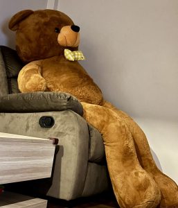 A giant teddy relaxing on a recliner 