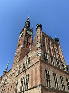 Historic brick building with clock towers against a clear blue sky
