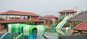 Resort swimming pool with water slides and shaded pavilions."