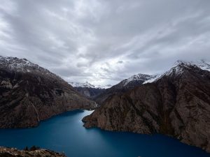 A serene blue lake framed by majestic mountains and fluffy clouds in a clear sky.