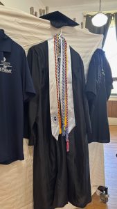 A gradtuation cap and gown hung on display.