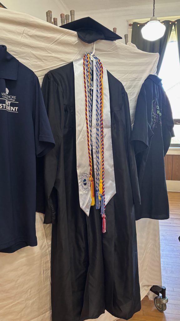 A gradtuation cap and gown hung on display.