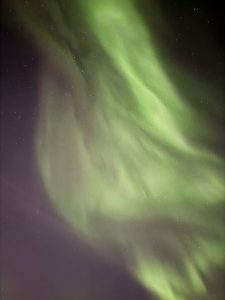 a mesmerizing view of the green aurora borealis in Tromsø, with stars visible against the dark sky in the background
