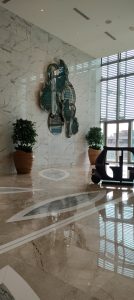 Modern hotel lobby with polished marble flooring, decorative wall art, and indoor plants.