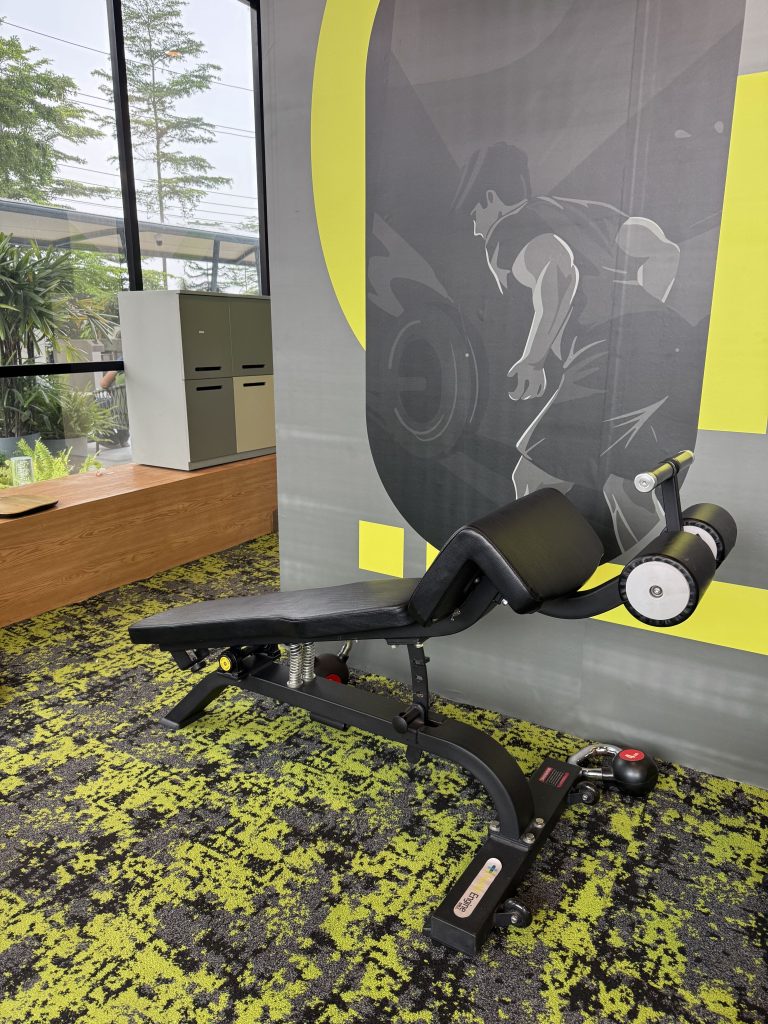 A black adjustable weight bench in a bright gym with a weightlifting mural and green-accented carpet