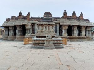 Intricately carved stone shrine and pillared temple hall at the Vittala Temple complex in Hampi, Karnataka, India.