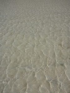 Rippling sea water creating a pattern over the sand
