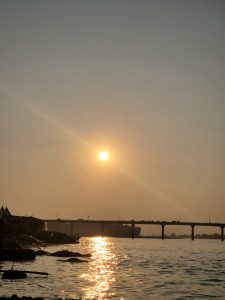 Sunset over a calm river with a bridge silhouetted against the golden sky. 
