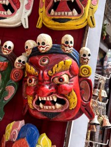 Fierce red Mahakala wooden mask with three eyes and a crown of skulls, used in Buddhist Cham dance ceremonies. 