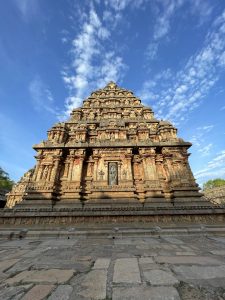 Ancient stone temple with intricate carvings, under a blue sky with scattered white clouds. 
