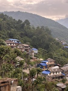 A image capturing the peaceful scenery of ghandruk village with vintage houses made up of stones wood and surrounded bye jungles greenery.