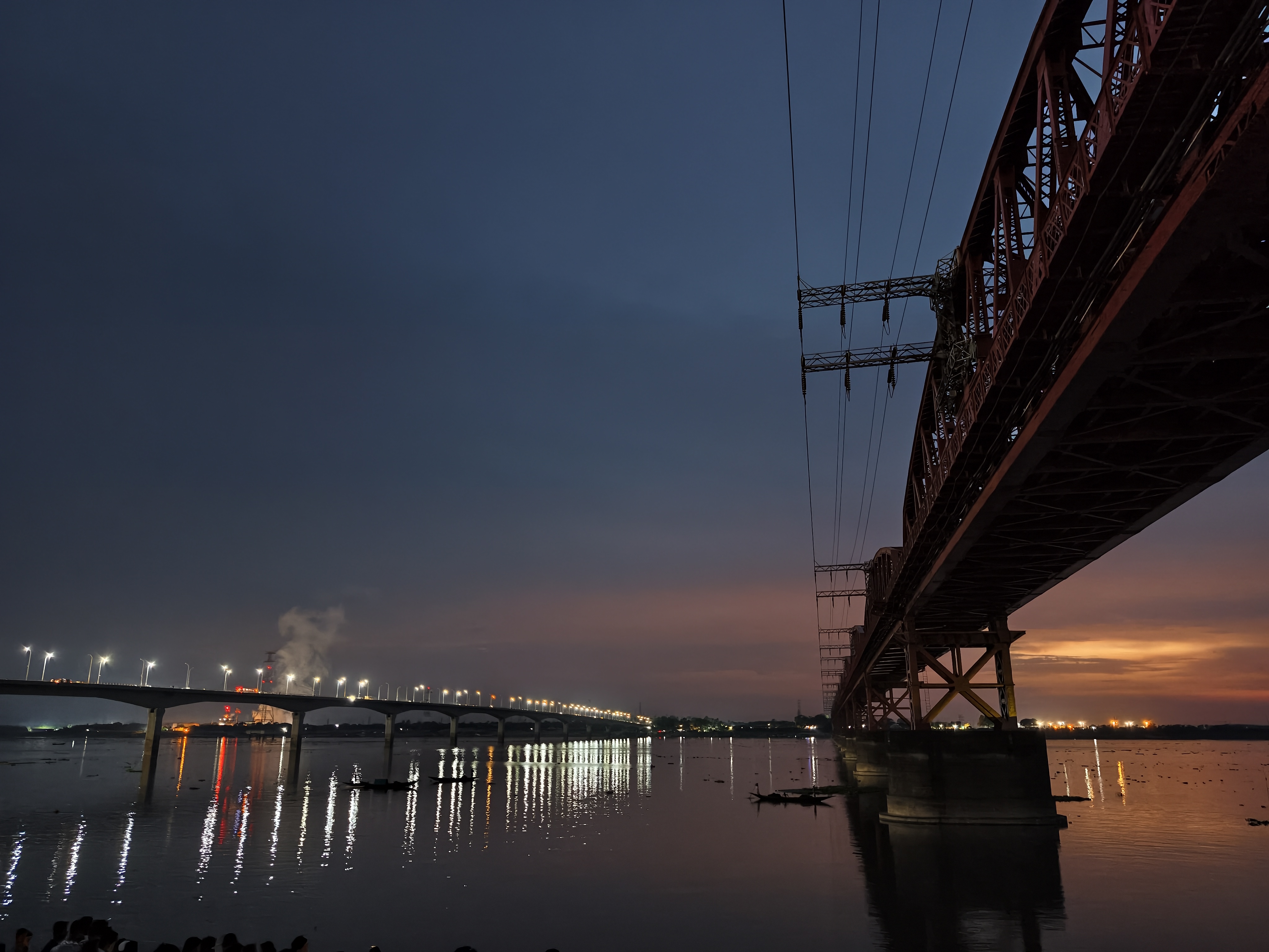 Hardinge Bridge and Lalon Shah Bridge illuminated at night over the Padma River, with shimmering reflections on the water and a colorful twilight sky between Pabna and Kushtia, Bangladesh.