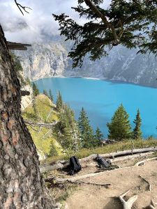 Scenic view of a turquoise lake surrounded by rocky cliffs and pine trees