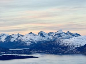 panoramic view of snow-capped mountains rises a soft pastel sky
