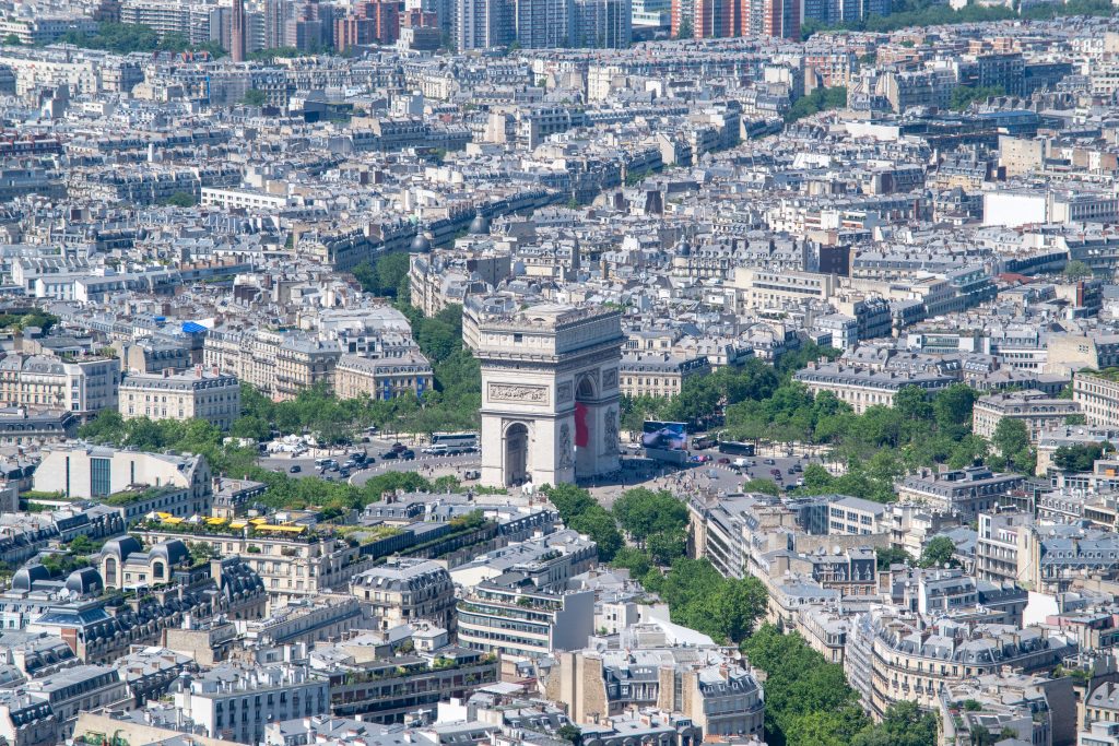This photo was taken from the Eiffel Tower. It shows a beautiful view of Paris, with the Arc de Triomphe visible in the distance. The streets and buildings create an impressive city landscape.