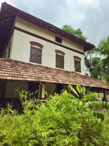 A beautiful view of a century-old building, showcasing traditional Kerala architecture with sloping tiled roofs, wooden windows, and lush greenery surrounding the heritage home. Captured at Varikkasseri Mana, Vaniyamkulam, Palakkad. 