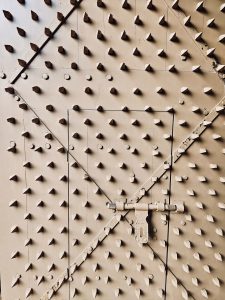 A close-up view of a massive fort door, once designed to strengthen defenses against attacks, now reinforced with iron spikes. The geometric pattern and aged texture highlight the fort’s historic architecture. Captured at St. Angelo Fort, Kannur, Kerala.
