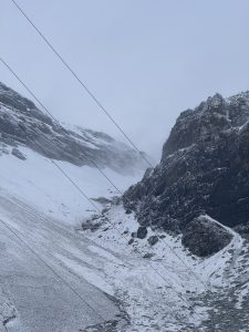 Wires and snow 

Snow-dusted rocky mountain landscape beneath a gray sky, with steel cables running diagonally,