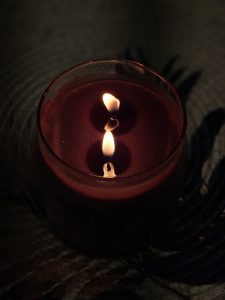 A glowing candle flame creates a beautiful reflection on the wax surface, forming a peaceful and artistic scene. The soft light and dark surroundings add warmth and a sense of calm. Captured at Perumanna, Kozhikode, Kerala.