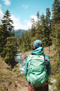Person looking out into the distance over a view of a creek flowing through a forest on either side with a mountain in the distance in Leavenworth, Washington, USA.