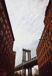 Manhattan Bridge tower piercing through a narrow canyon of historic red brick warehouses 
