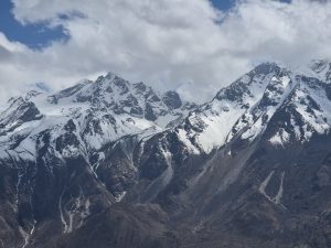 Snow capped mountains under a partly cloudy sky. 
