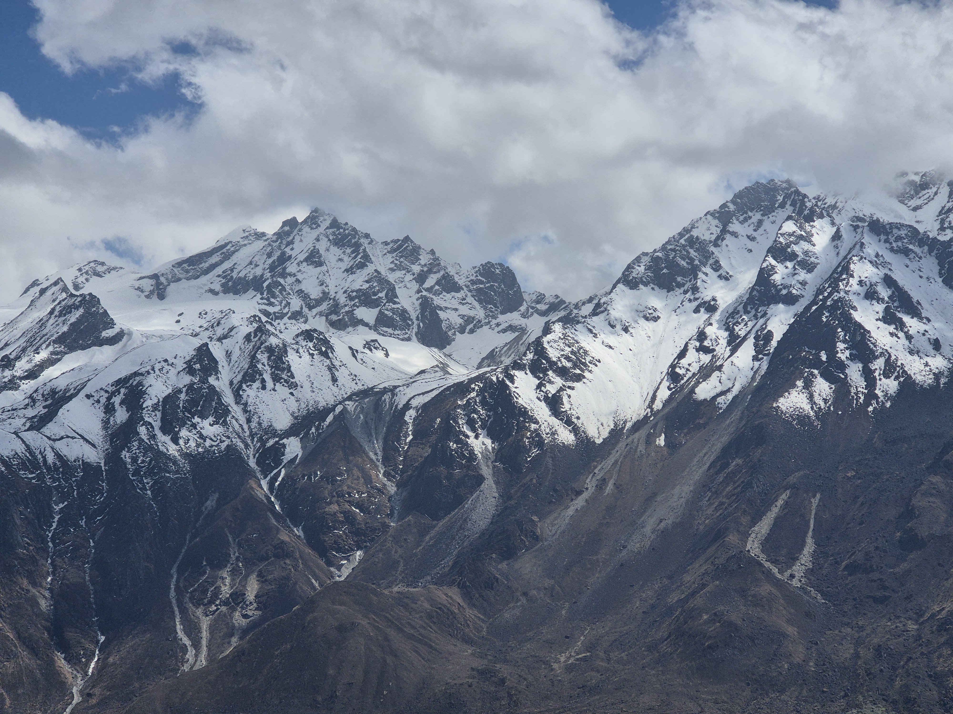 Snow capped mountains under a partly cloudy sky.