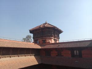 Historic brick tower with beautiful wooden carvings at Hanuman Dhoka Durbar Square, Kathmandu, Nepal, under a clear blue sky.
