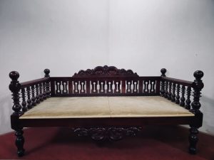 A beautifully crafted wooden daybed with carved details and turned balusters reflects the elegance of traditional Arakkal-era furniture. Its polished finish and sturdy design showcase the craftsmanship of a bygone era. Captured at Arakkal Museum, Arakkalkettu, Kannur, Kerala.