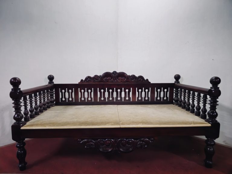 A beautifully crafted wooden daybed with carved details and turned balusters reflects the elegance of traditional Arakkal-era furniture. Its polished finish and sturdy design showcase the craftsmanship of a bygone era. Captured at Arakkal Museum, Arakkalkettu, Kannur, Kerala.