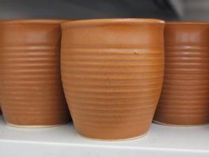 A row of handcrafted ceramic cups showcases the beauty of traditional pottery. Their warm, earthy tones and simple design reflect everyday craftsmanship and cultural heritage. Captured at Palazhi, Kozhikode.
