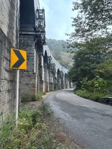 Stone arch railway bridge winding through a forested hillside 