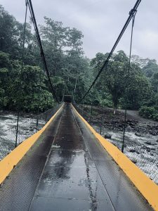 A suspension bridge crossing a river in a tropical rainforest after rainfall in Costa Rica.