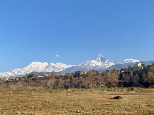 A sweeping panoramic view of Pokhara valley with Phewa Lake and the Annapurna mountain range with Machhapuchhre peak rising above the clouds. 