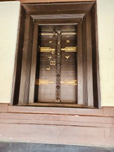 An elegant wooden door, adorned with brass fittings and traditional motifs, reflects the fine craftsmanship of Kerala's historic mansions. Captured at Varikkasseri Mana, Vaniyamkulam, Palakkad.