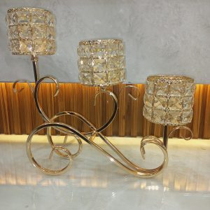 Elegant candle holder with three golden, crystal-embellished cups on a swirling metal base
