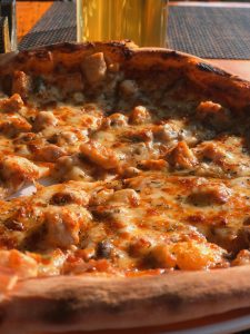 A close up of a freshly baked chicken pizza with golden melted cheese. 