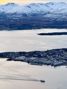 a bird's-eye view of the island and a boat, with the sun setting behind the mountains